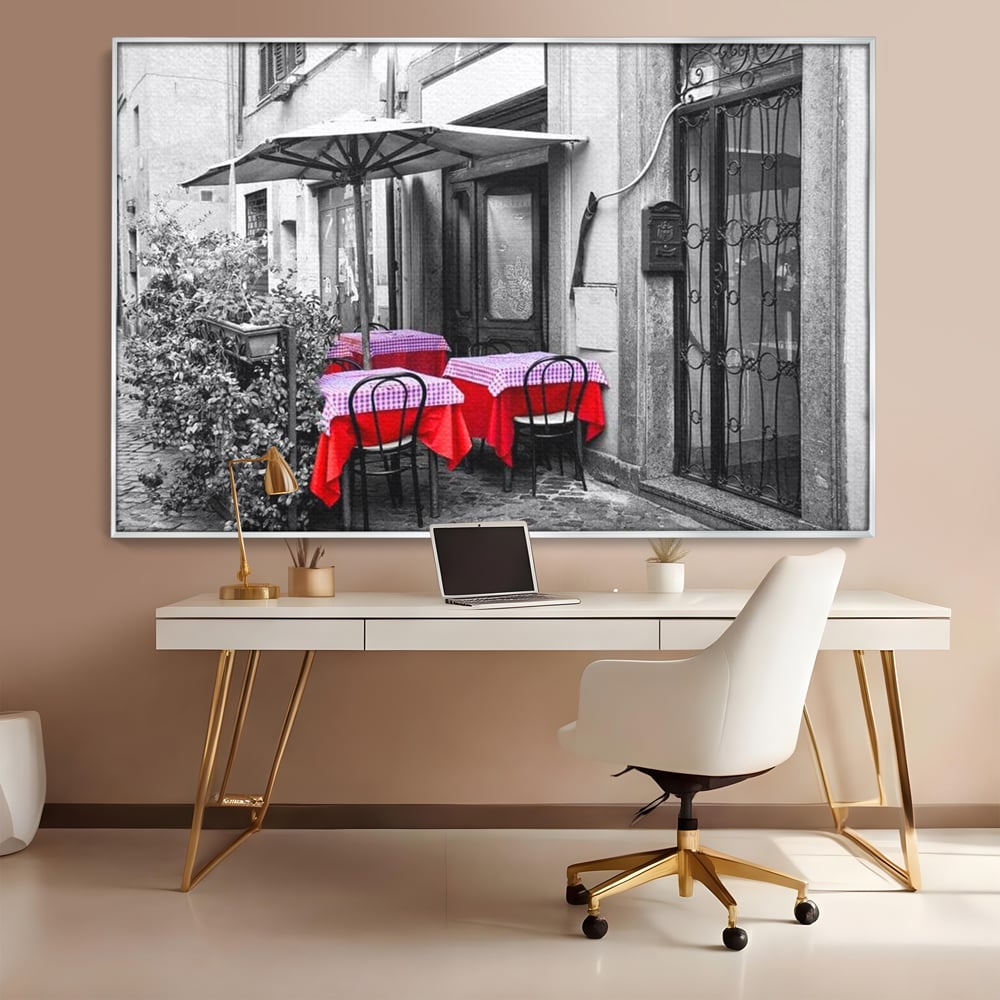 Tablou canvas cu cafenea stradala vintage alb negru cu pete de rosu, in rama de aluminiu argintiu, pe perete intr-un birou